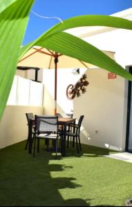 a table and chairs under an umbrella on a lawn at Bungalow La Palmera - 2 bedroom - PLAYA ROCA residence sea front access - Pool View - Free AC - Wifi in Costa Teguise