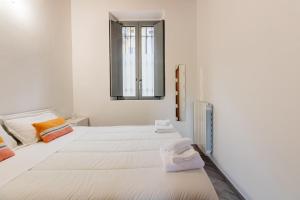 Habitación blanca con 2 camas y espejo. en Homeby - Apartment Anna Maria en Corsico