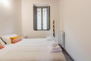 a white room with two beds and a mirror at Homeby, Loft Anna Maria in Corsico
