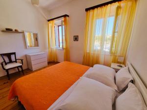 a bedroom with a bed and a chair and windows at Apartments Lukrecia in Hvar