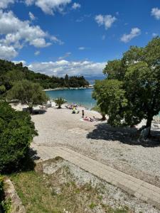a beach with people laying on the sand and the water at Apartments F&T in Mošćenička Draga