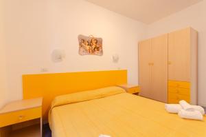una piccola camera da letto con un letto e una testiera gialla di Residence L'Uliveto a Mattinata
