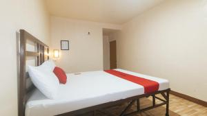 a small room with a bed with white and red sheets at RedDoorz at Elegance Guest House near NAIA T3 in Manila