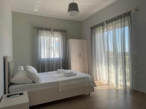 a white bedroom with a bed and a large window at Villa Almando in Ksamil