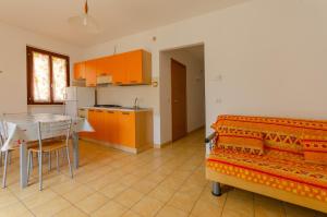 un soggiorno con tavolo e una cucina con armadietti arancioni di Residence L'Uliveto a Mattinata