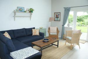 ein Wohnzimmer mit einem blauen Sofa und Stühlen in der Unterkunft Lustrup Farmhouse in Ribe