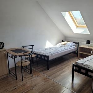 トチェフにあるPokojeのベッドルーム1室(ベッド1台、テーブル、ベッド1台、窓付)