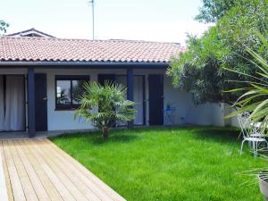 a house with a green yard with a wooden walkway at Chambres d'Hôtes En Aparté in Toulouse