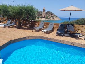 a swimming pool with chairs and an umbrella at Beachfront Villa Phi φ in Agios Nikolaos