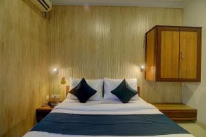 OYO SilverKey Hotel Manas Residency في مومباي: غرفة نوم مع سرير مع الوسائد وخزانة