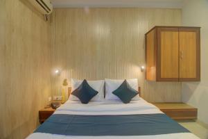 OYO SilverKey Hotel Manas Residency في مومباي: غرفة نوم مع سرير ووسائد زرقاء وبيضاء