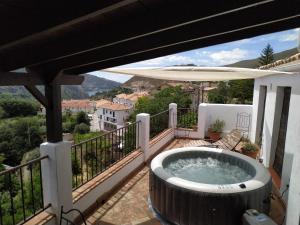 - Balcón con bañera de hidromasaje y sombrilla en Casa Rural Arroyo de la Greda en Güéjar-Sierra