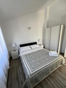 1 dormitorio con 1 cama grande, paredes blancas y suelo de madera. en Sunce apartments en Grebaštica
