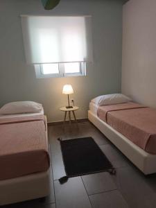 a bedroom with two beds and a table with a lamp at 3 BEDROOMS BEAUTIFUL COMFORTABLE APARTMENT IN RODOS TOWN in Rhodes Town