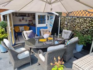 a table and chairs with an umbrella on a patio at Dungarvon House B&B, Exclusive Bookings Only, Hot tub, Garden & Summerhouse, EV Point in Weston-super-Mare