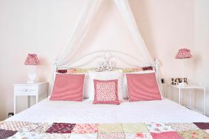een slaapkamer met een wit bed met rode kussens bij Case del Vicolo Stretto in Modica