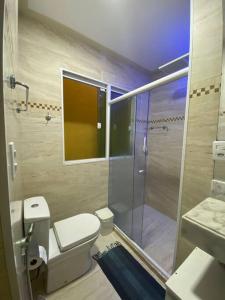 a bathroom with a toilet and a glass shower at Casa do Mar Stella Maris in Salvador