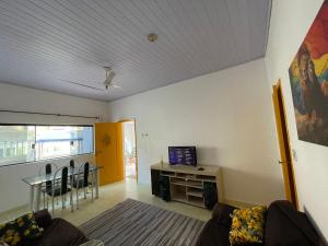 a living room with a table and a tv on a wall at Casa Praia Grande in Praia Grande
