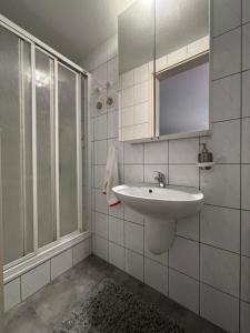 un bagno bianco con lavandino e doccia di Doppelzimmer in Stuttgart-Birkach - Nähe Musicals im SI-Zentrum, Messe, Flughafen, Uni Hohenheim a Stoccarda