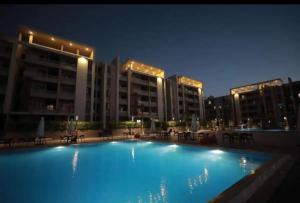 ein großes Schwimmbad vor Gebäuden bei Nacht in der Unterkunft Chalet Grand Hills North coast in Dawwār al Ḩajj Aḩmad + 9 Fotos