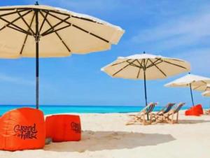 eine Gruppe von Sonnenschirmen und Stühlen am Strand in der Unterkunft Chalet Grand Hills North coast in Dawwār al Ḩajj Aḩmad