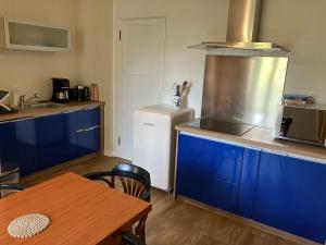 a kitchen with blue cabinets and a white refrigerator at Ker Heol in Saint Malo +1 photo