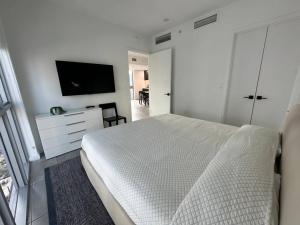 a white bedroom with a bed and a tv at Apartamento en Downtown Miami in Miami
