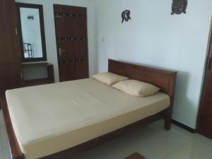 Schlafzimmer mit einem Bett mit einem Kopfteil aus Holz in der Unterkunft Cottage 23 in Kurunegala