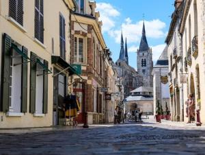 een stadsstraat met gebouwen en een kerk bij Tout à pied Dourdan Appartement in Dourdan
