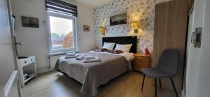 een slaapkamer met een bed met een stoel en een raam bij Bed & Breakfast Moments in Schagen