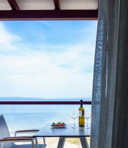 a table with two glasses and a bottle of wine at Elpiniki Luxury Rooms in Nea Potidaea