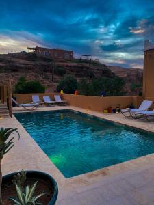 a swimming pool with chairs and a view of the desert at Kasbah Isfoula and Spa in Aït Benhaddou