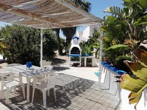 a patio with white tables and chairs and a grill at Sole&Mare in Monopoli