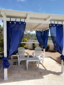 a gazebo with two chairs and blue curtains at Sole&Mare in Monopoli