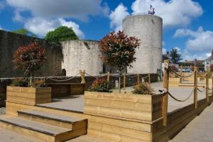 een keermuur met wat bomen in houten kisten bij Tout à pied Dourdan Appartement in Dourdan