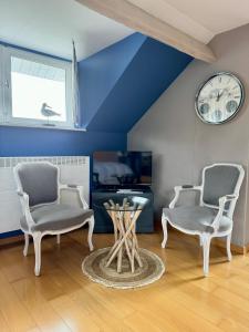 2 Stühle und ein Tisch in einem Zimmer mit einer Uhr in der Unterkunft La Borzeux in Stavelot
