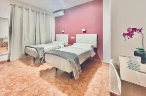 duas camas num quarto de hospital com paredes cor-de-rosa em Hostal Rocamar em Almuñécar