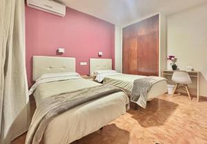 2 Betten in einem Zimmer mit rosa Wänden in der Unterkunft Hostal Rocamar in Almuñécar