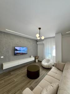 a living room with a couch and a tv on a wall at Elysian Escape Apartment in Sarandë