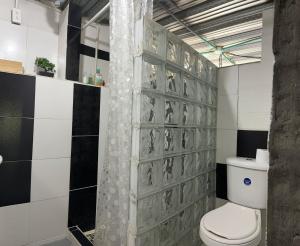 a bathroom with a toilet and a tile wall at Villa Isa in Cali