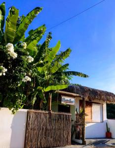 une petite maison avec un toit de chaume et une clôture dans l'établissement Pousada Tangerina, à Icaraí