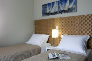 a hotel room with two beds and a book on a table at Ilios villa in Fternón +10 photos