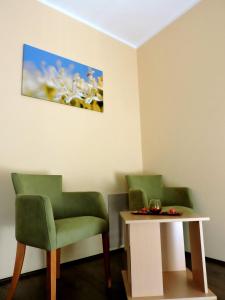 duas cadeiras verdes e uma mesa num quarto em B&B Zmajevo Gnezdo 021 em Sremska Kamenica