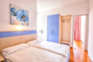 a bedroom with a white bed and a blue cabinet at Residence Wieland in Torri del Benaco