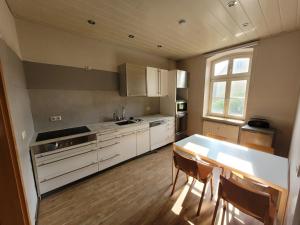 a kitchen with white cabinets and a table and chairs at Haus am See Annahütte - für bis zu 6 Personen in Schipkau