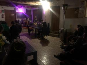 um grupo de pessoas sentadas numa sala com um homem num palco em Intihuatana Hostel em Pisac