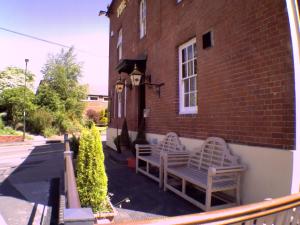 two benches sitting on the side of a brick building at The Bulls Head in Swadlincote