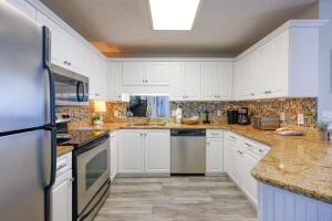 a kitchen with white cabinets and marble counter tops at Phoenix V 1403 condo in Orange Beach