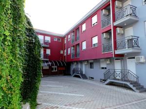 Sremska Kamenica的住宿－B&B Zmajevo Gnezdo 021，停车场里一座红色的建筑,有楼梯