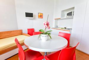 Residence Wieland في توري ديل بيناكو: غرفة صغيرة مع طاولة بيضاء وكراسي حمراء